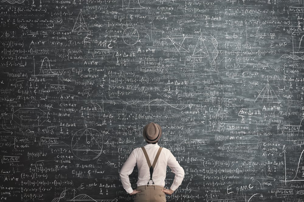 Homem olhando para um quadro negro com diversas fórmulas